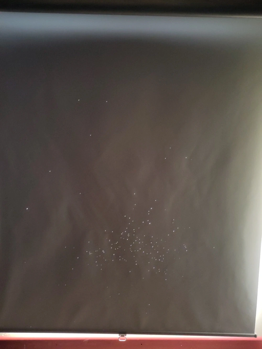 A window blind with many tiny holes poked in it.