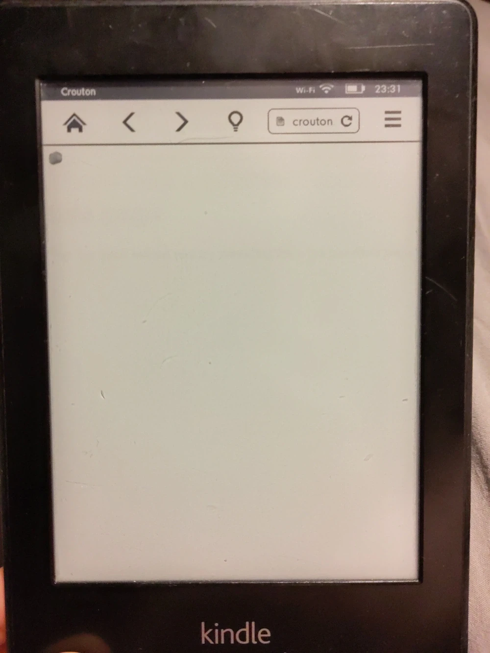 An old Kindle displaying a tiny black and white image of a crouton in the corner of the display.