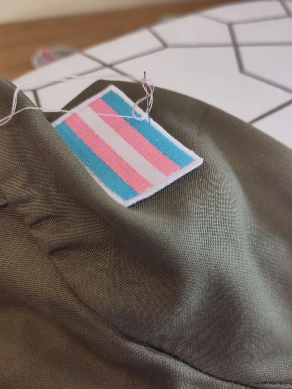 A transgender pride flag being sewn in its place.